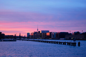Scenic twilight cityscape with calm river Spree, skyline, and vibrant purple and pink sky. Berlin, Germany