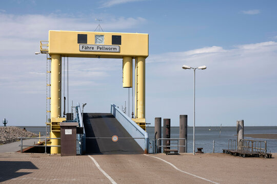 Yellow ferry terminal with ramp leading to water on a sunny day at Pellworm. North Sea, Germany