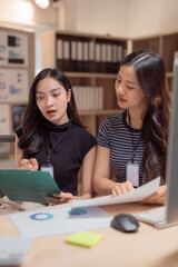 Two young businesswomen are discussing financial data in a modern office, collaborating on documents and analyzing charts to make informed business decisions