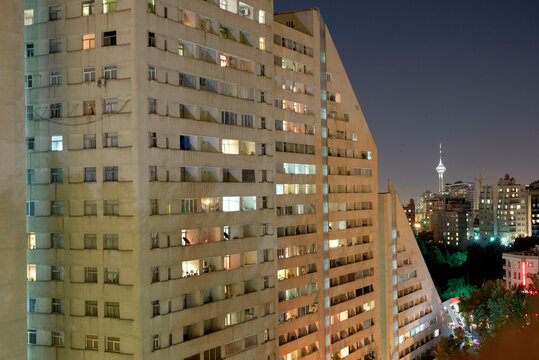 Illuminated high-rise apartment buildings at night with city skyline in the background. Tehran, Iran