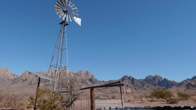 Windmill Pumping Water with Mountains Behind it