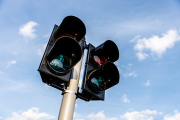 Pedestrian crossing traffic lights at an intersection against blue sky