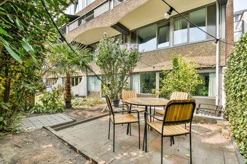 Obraz premium A cozy outdoor seating area featuring simple furniture amidst vibrant plants, perfect for relaxing or entertaining in a tranquil environment.