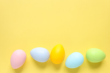 Easter eggs painted in pastel colors on a yellow background. Easter celebration concept. Colorful easter eggs with place for text.