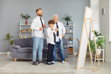 Happy smiling family of father, child boy and senior grandfather standing in living room at home...
