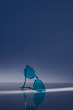 Stylish Blue Sunglasses on Reflective Surface