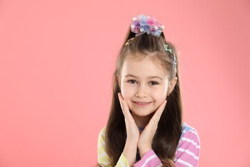 Happy little girl wearing beautiful hair accessories on pink background, space for text
