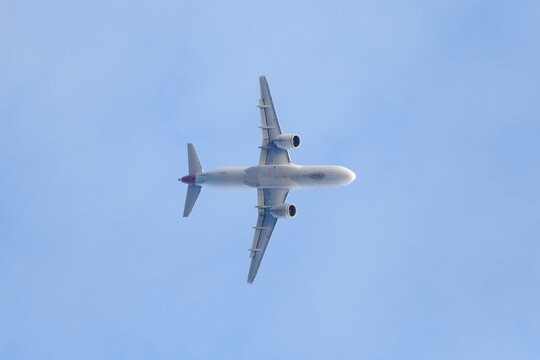 A  shot from below of a white airplane preparing to land.