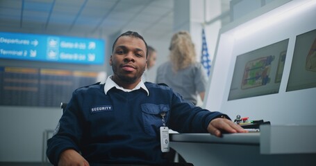 Airport Security Checkpoint: Portrait of African American TSA Worker Looking at Camera. Computer...