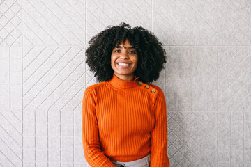 Woman Smiling in Orange Sweater Against Textured Wall