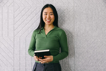 Young professional woman holding notebook and smiling confidently