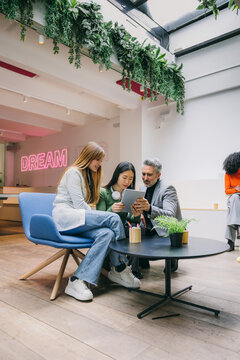 Creative workspace with diverse team collaborating on tablet