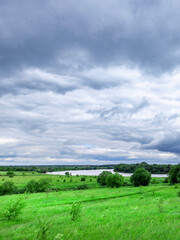 Cloudy sky with a green field in the background