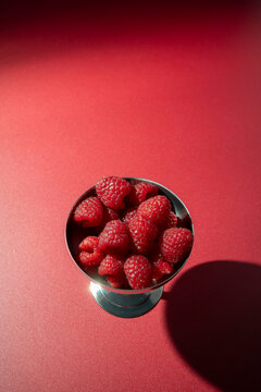 Fresh Raspberries in a Metal Cup on Red Background