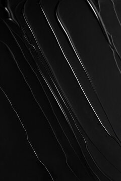 Smears of black glossy lip shine on a gray background.