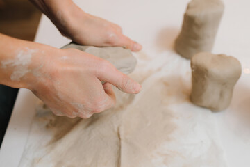 Hands of a female potter making ceramic clay product on the table in the pottery workshop. Potter...