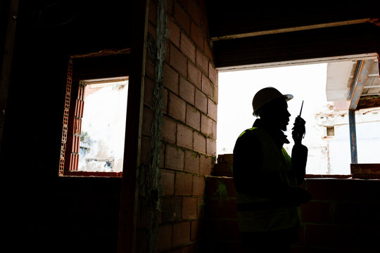 Construction worker communicating with walkie talkie inside building