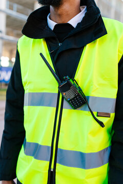 Security guard wearing high visibility vest and using walkie talkie