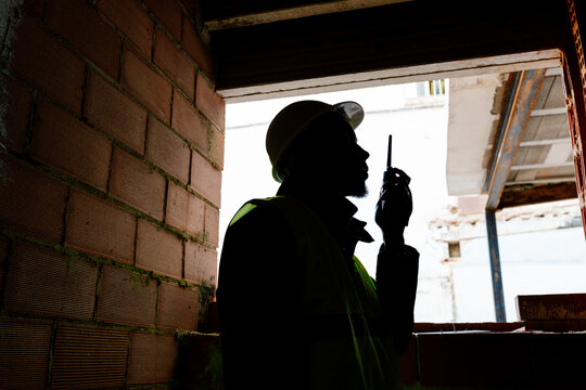 Construction worker communicating with walkie talkie on building site