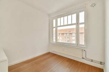 A spacious, bright room featuring large windows that offer ample natural light, minimalistic design, and wooden flooring, ideal for modern living.