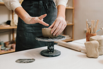Female potter hands shows ceramic bowl ready for firing in a kiln. The process of creating ceramic products.
