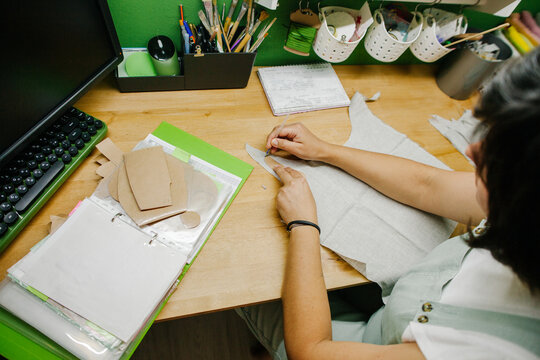 A woman draws out a toy pattern on fabric.