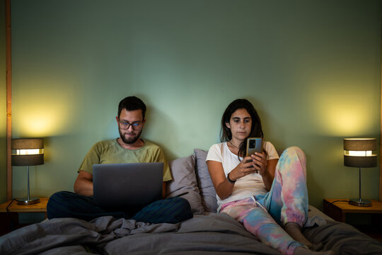 young Couple Using digital devices in Comfortable Bedroom