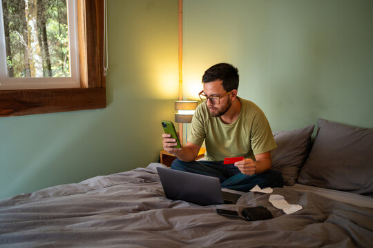 man using laptop and credit card while paying bills