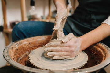 Potter sculpts a ceramic mug from clay in the pottery studio. Molding earthenware with potters...