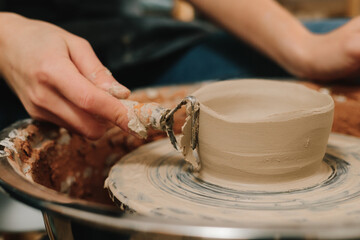 Artisan forms clay pot with potters tool on the spinning wheel. Creating ceramic earthenware on the manufacturing.