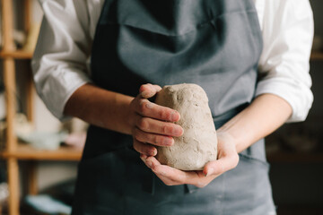 Process of creating ceramic products. Potter holds a piece of wet clay in their hands, molds it into form.
