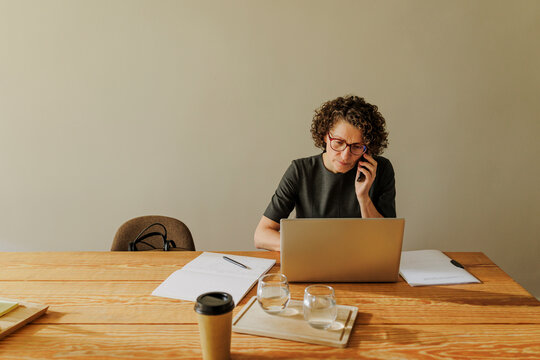 Focused entrepreneur working on laptop and talking on phone at office