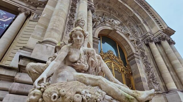 Close-up view of a stone statue of a reclining woman near the Petit Palais golden gate, Paris, France.