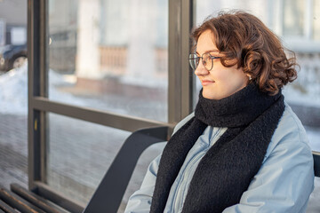 Teenage girl waiting for public transportation. Girl at the bus stop.