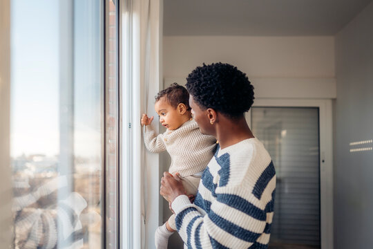 Father holding his baby looking out the window