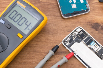 disassembled phone display and voltage measurement tools