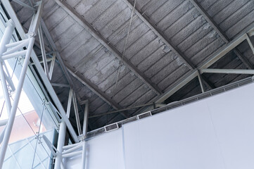 Obraz premium modern industrial ceiling with exposed metal beams and insulation, complemented by large glass windows and white walls, creating clean and minimalist architectural design