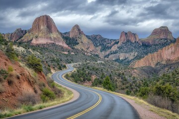 Fototapeta premium Majestic highway winding through dramatic mountains under stormy skies