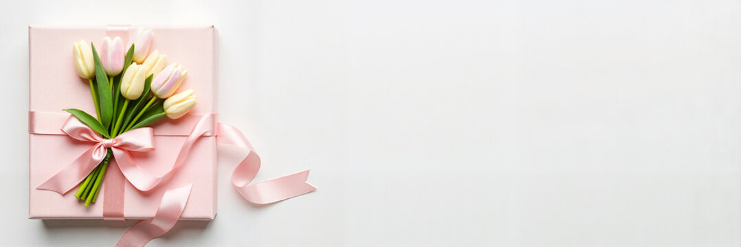 Beautifully wrapped floral gift with exquisite tulips and satin ribbon on a white surface, elegant design for celebrations and special occasions.