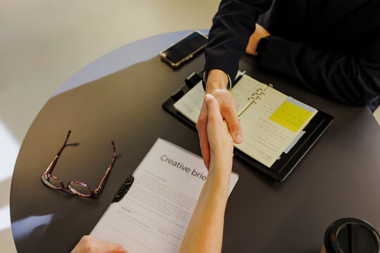 Business people shaking hands after signing creative brief contract