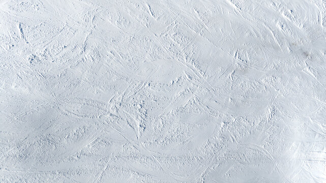 Aerial view of a snowy terrain ideal for textures, patterns and backgrounds. The white snow completely covers the ground.