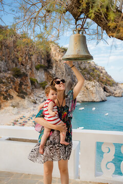 Mother and her son ringing a bell in a shrine near a beach