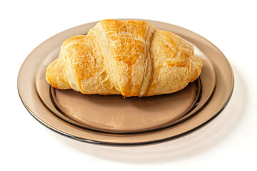 freshly baked flavorful crispy croissant on a glass plate isolated on white