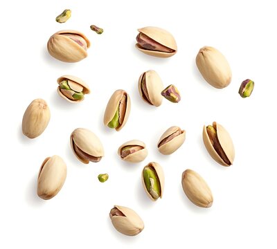 A top view of pistachios falling against a clean white background, showcasing their vibrant green shells and unique shapes in a dynamic, scattered arrangement.