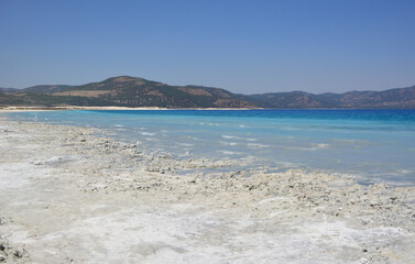 Turquoise Lake Shore with Mountains Under Blue Sky