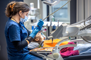 Young female dentist in dental office. Dentist at work. Dental treatment concept.