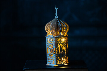 ornamental Arabic lantern with burning candle glowing at night. Festive greeting card for Muslim...