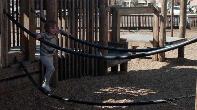 Little Toddler Girl Playing on a Tight Rope at a Playground