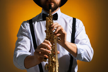 Professional musician playing soprano saxophone on color background, closeup