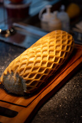 A close-up of a golden, flaky puff pastry with a delicate lattice pattern, placed on a wooden cutting board in a cozy kitchen atmosphere.